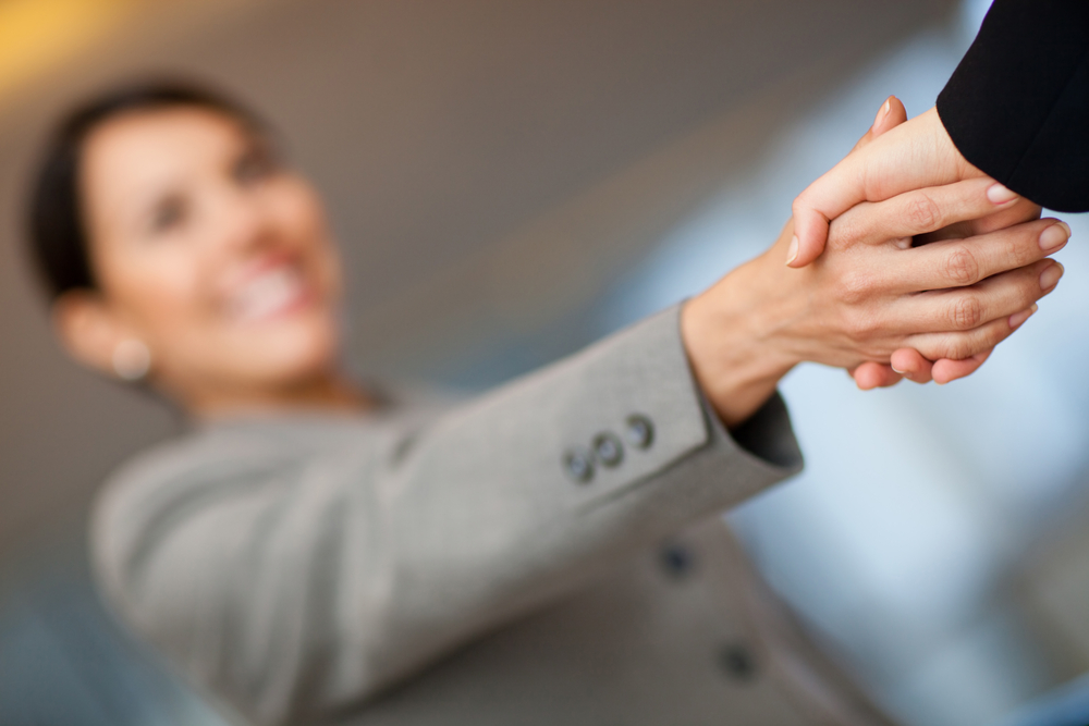Welcoming business woman giving a handshake and smiling Welcoming business woman giving a handshake and smiling